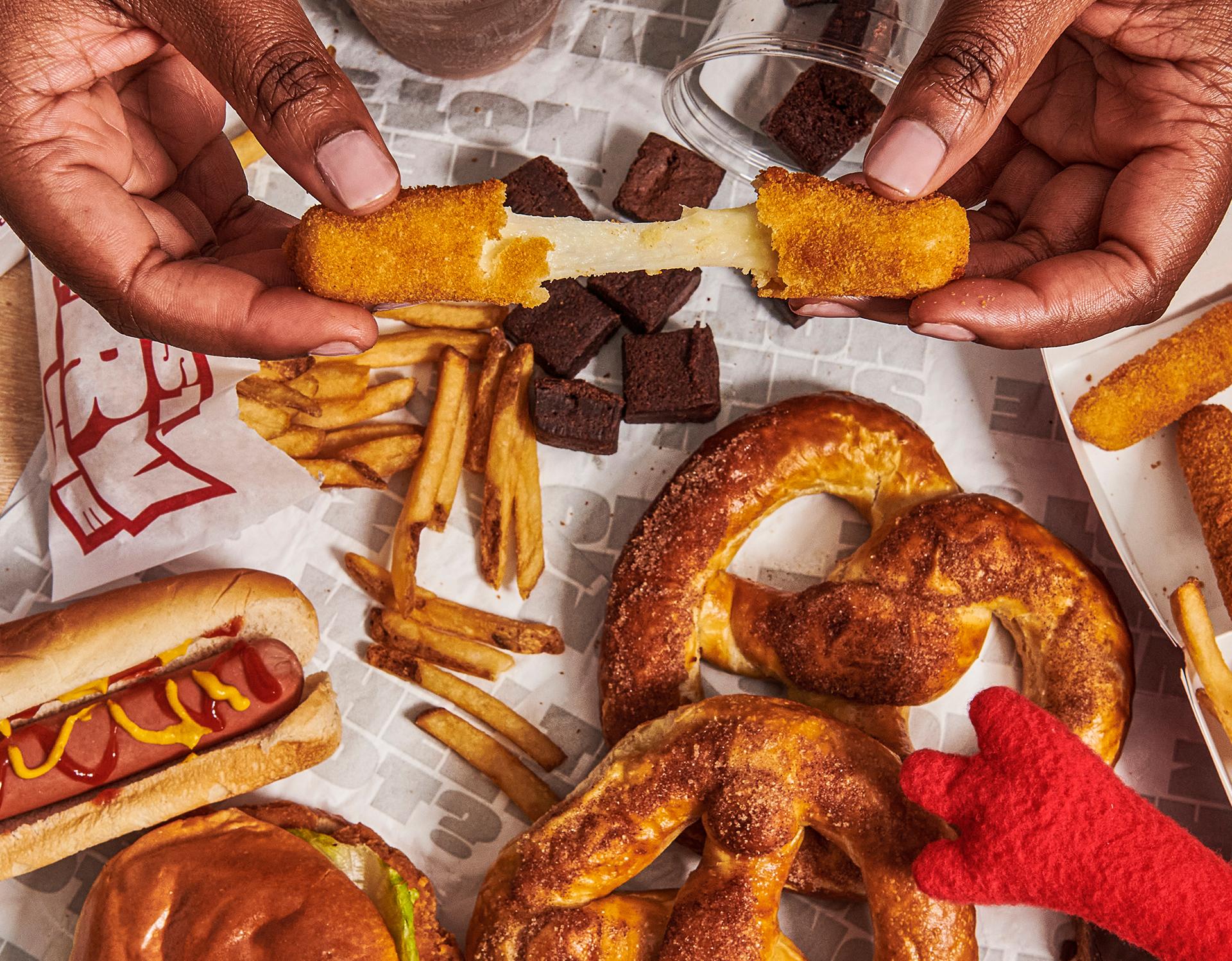 pulling apart a mozzarella stick with an assortment of other sheetz food items