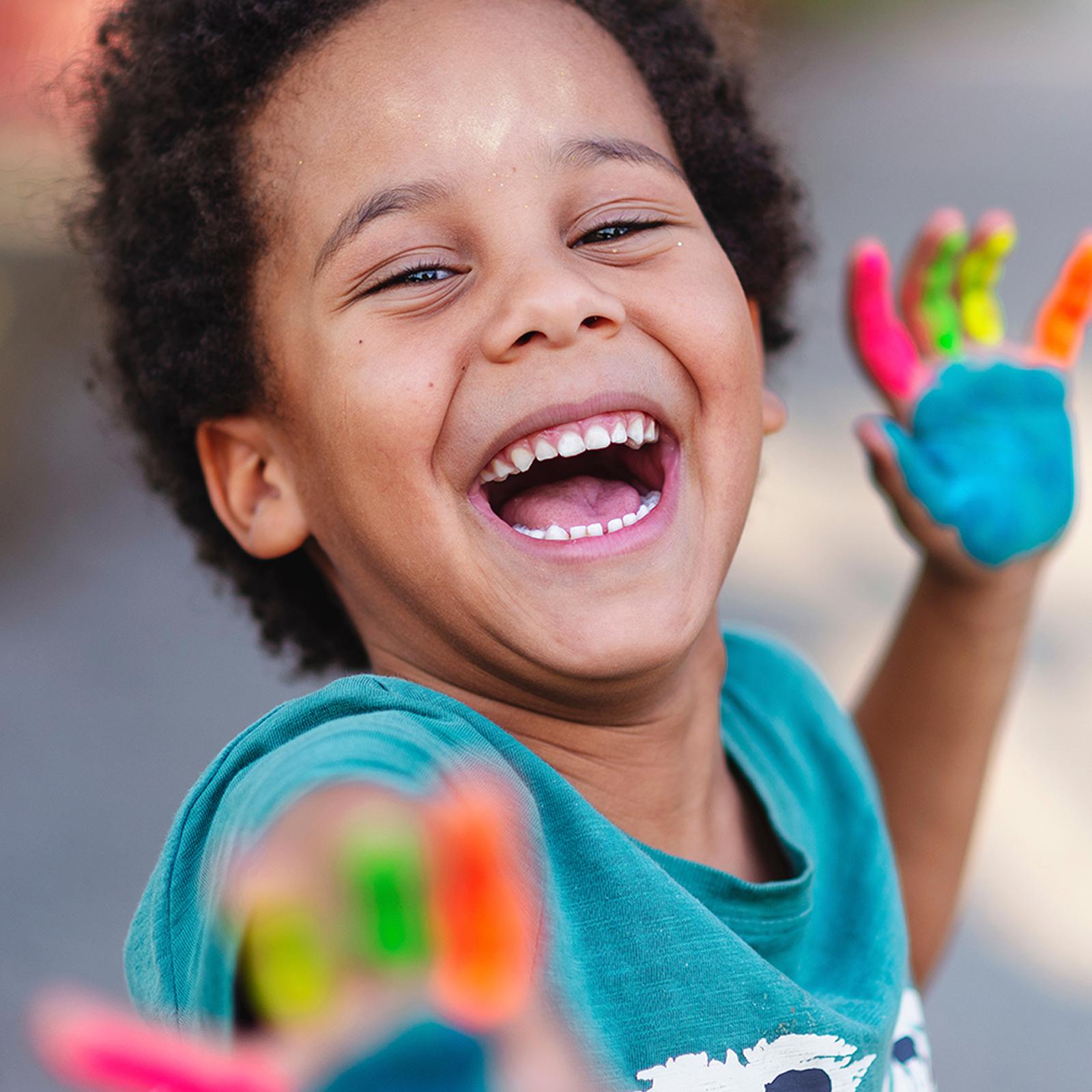 boy with painted hands smiling outside